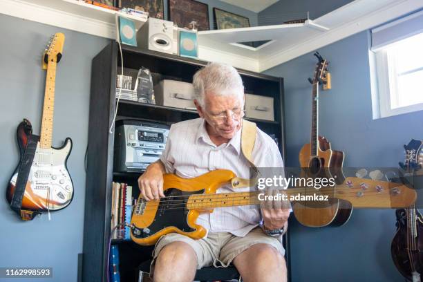 senior man playing bass in his studio - electric guitar stock pictures, royalty-free photos & images