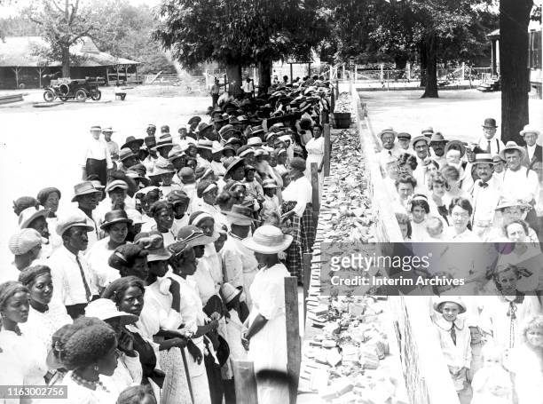 View of crowds at an annual barbecue given on the plantation of FM Gay, Alabama, 1930s. The crowds are segregated.