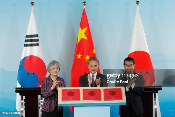 Chinese Foreign Minister Wang Yi , South Korean Foreign Minister Kang Kyung-wha and Japanese Foreign Minister Taro Kono clap during a ceremony to...