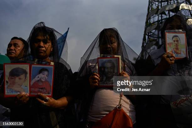 Relatives and friends of victims of extra-judicial killings hold pictures of their deceased kin as they participate in participate in a National Day...