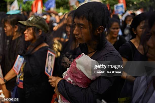 Relatives and friends of victims of extra-judicial killings hold pictures of their deceased kin as they participate in participate in a National Day...