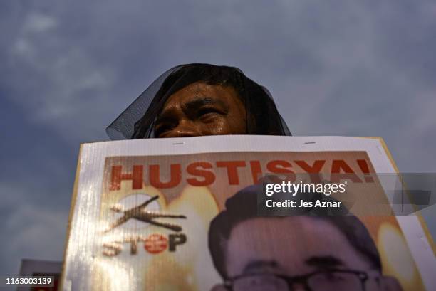 Relatives and friends of victims of extra-judicial killings hold pictures of their deceased kin as they participate in participate in a National Day...