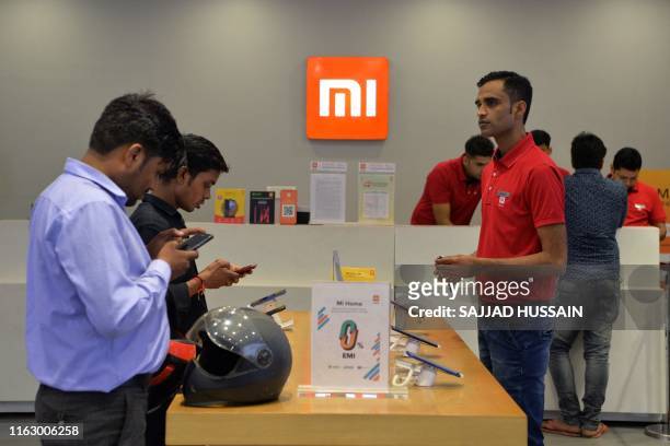 In this photograph taken on August 20 customers inspect smartphones made by Xiaomi at a Mi store in Gurgaon.
