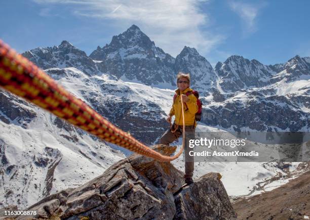 kletterseil führt zum bergführer auf felsgipfel - guide stock-fotos und bilder