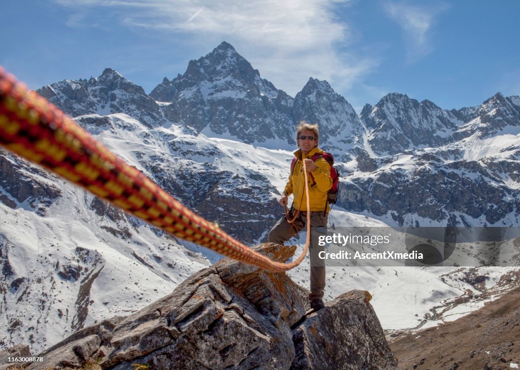 Climbing rope leads to mountain guide on rock summit