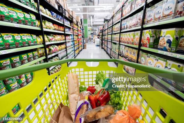 carrello della spesa lungo il corridoio del supermercato pieno di generi alimentari - wagon foto e immagini stock
