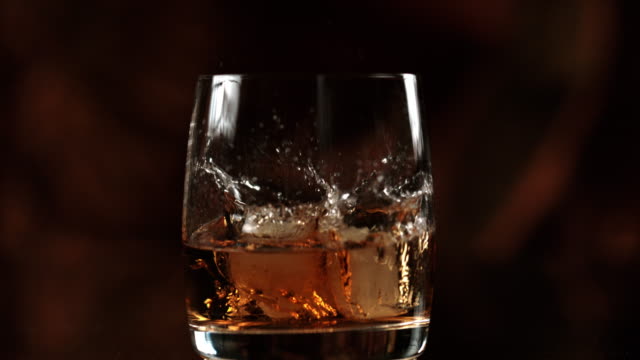 SLO MO Adding ice to a whiskey