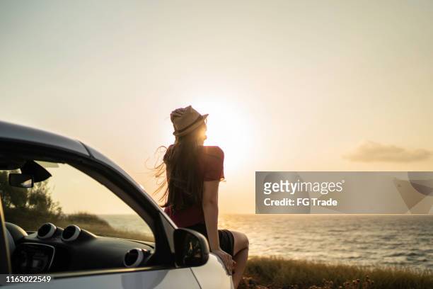 rear view of a woman sitting in a car looking at view - journey to the day stock pictures, royalty-free photos & images