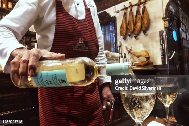 Spanish bartender serves white wine in the iconic Casa Alberto tapas bar and restaurant on March 21, 2019 in the heart of Madrid, Spain's vibrant...