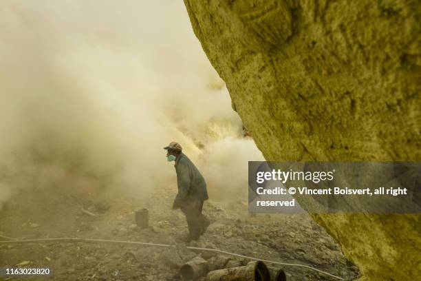 june 2017, sulfur miner walking in the sulfuric fog with his gas mask, kawah ijen, java, indonesia - sulfuric acid stock pictures, royalty-free photos & images