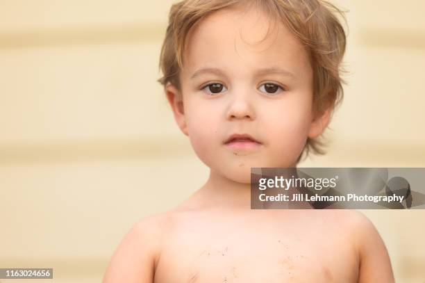 portrait of a serious male 3 year old toddler without a shirt - summer camp stock-fotos und bilder