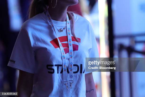 An employee wears a Stadia cloud gaming streaming service branded t-shirt on the Google Inc. Exhibition stand at the Gamescom gaming industry event...
