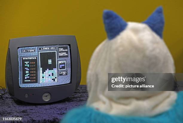 August 2019, North Rhine-Westphalia, Cologne: At Gamescom, a disguised trade fair visitor plays on a Tetris television set in the retro games area....