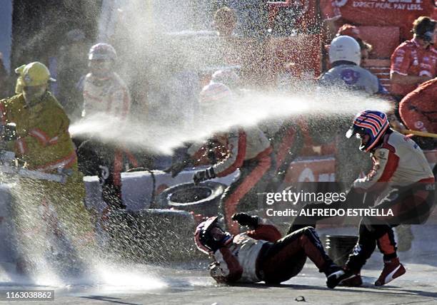 Mechanic of the Brazilian racecar driver Tony Kanaan, of the Monunn Racing team, is helped by his teammate after suffering an accident in the pits...