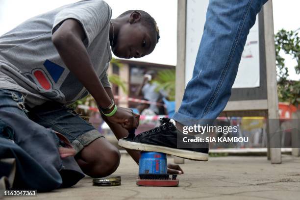 Shoeshine boy works at his booth on a street of the working class Yopougon district of Abidjan, Ivory Coast, on August 21, 2019.
