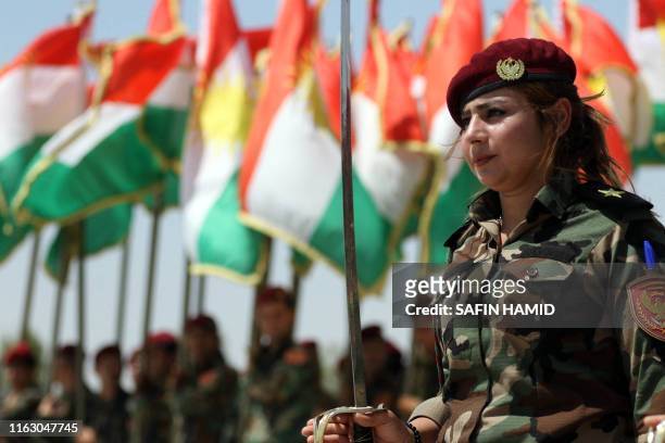 Woman fighter of the Iraqi Kurdish Peshmerga attends a ceremonial line-up past flying flags of Iraq's autonomous Kurdistan region, during a training...