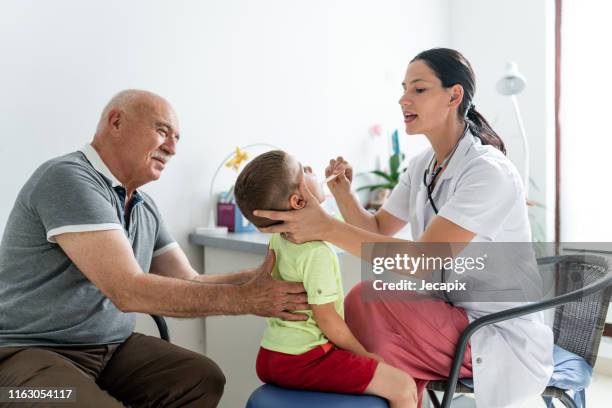 kleine jongen is het hebben van pediatrische examen - throat exam stockfoto's en -beelden