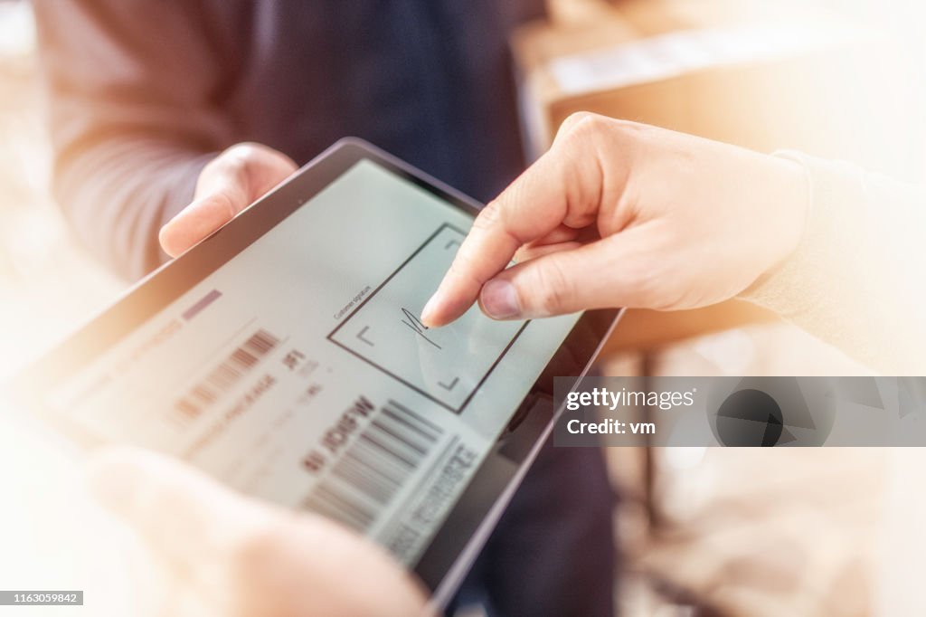Kunden unterzeichnen Empfang der Hauszustellung auf einem Tablet