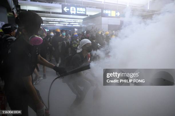 Protesters use fire extinguishers during a protest at the Yuen Long metro station in Hong Kong on August 21, 2019. - Hundreds of masked protesters...