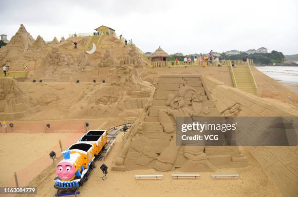 Tourists watch sand sculptures during the 21st China Zhoushan International Sand Sculpture Festival at Zhujiajian resort on July 19, 2019 in...