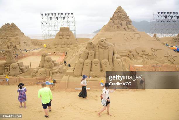 Tourists watch sand sculptures during the 21st China Zhoushan International Sand Sculpture Festival at Zhujiajian resort on July 19, 2019 in...