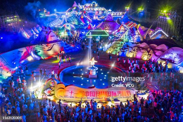 Tourists watch illuminated sand sculptures during the 21st China Zhoushan International Sand Sculpture Festival at Zhujiajian resort on July 19, 2019...