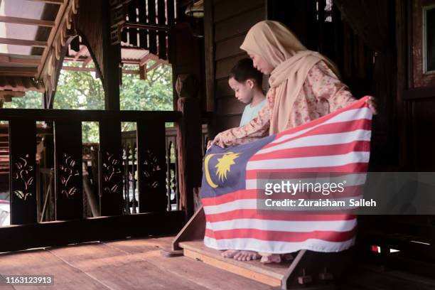donna musulmana malese in abito tradizionale con la bandiera durante la celebrazione della merdeka a casa - malaysia independence day foto e immagini stock