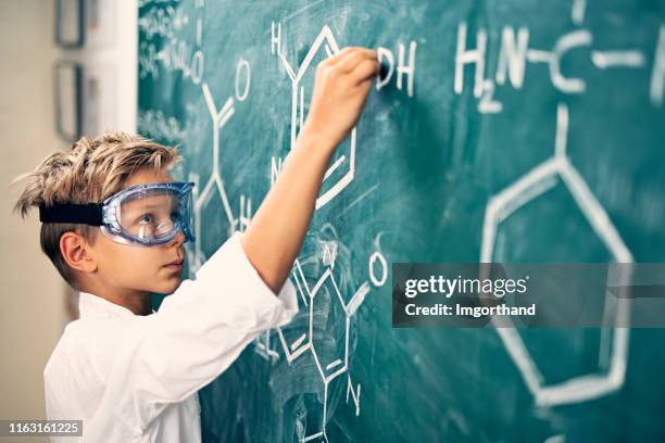 kleine jongen die chemische formules op het blackboard schrijft - uitvinder stockfoto's en -beelden