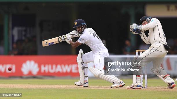Sri Lankan cricket captain Dimuth Karunaratne plays a shot as New Zealand wicket keeper BJ Watling looks on during the first day's play of the second...