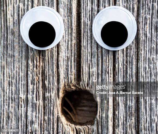 drawing of a face and smiling eyes on a old wooden door. - googly eyes stock pictures, royalty-free photos & images
