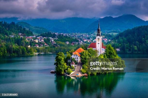 beautiful view of pilgrimage church of the assumption of maria, famous bled island (blejski otok), and scenic bled lake, with julian alps in the background, slovenia, europe. - bled slovenia stock pictures, royalty-free photos & images