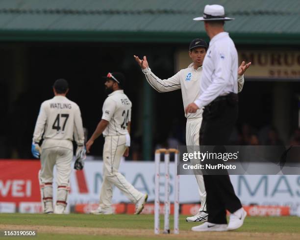 New Zealand cricketer Ross Taylor talks to umpire Michael Gough as the play is called off due to bad light during the first day's play of the second...