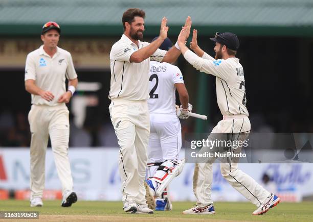 New Zealand cricketer Colin de Grandhomme celebrates after taking the wicket of Sri Lankan cricketer Kusal Mendis with New Zealand cricket captain...