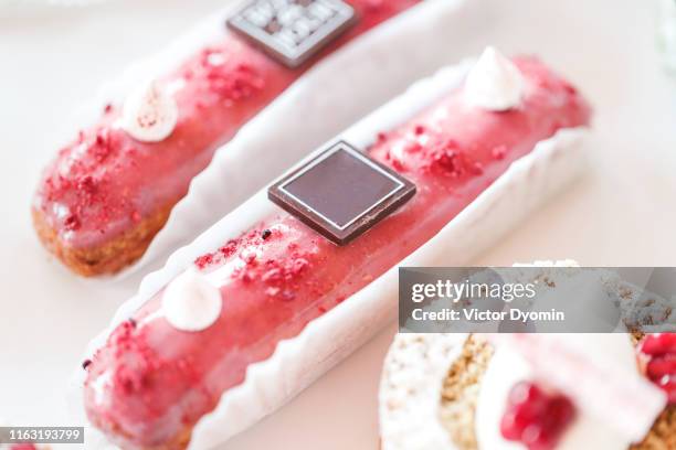 pink eclairs lie on beautiful saucers on the table - eclair stockfoto's en -beelden