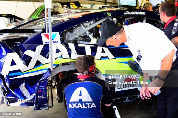 Crew member for Alex Bowman, driver of the Axalta Chevrolet, and a NASCAR official look over the damage following an on-track incident during...