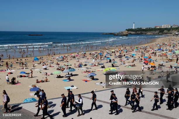 French CRS riot police officers patrol next to tourists sunbathing at the Grande Beach in Biarritz, southwestern France on August 22 where G7...