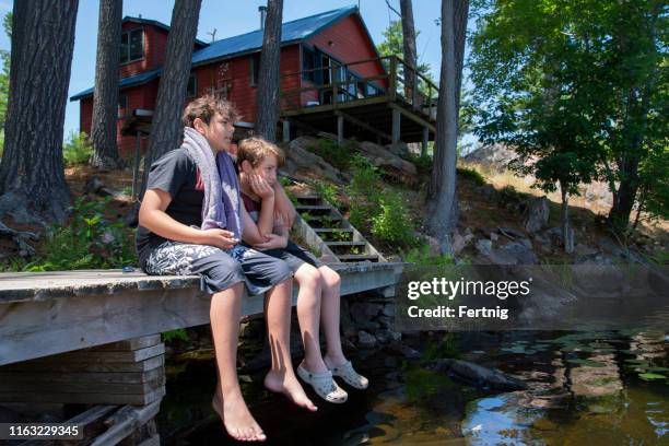 two bothers relaxing on the dock of an island cabin or cottage. - cottage imagens e fotografias de stock
