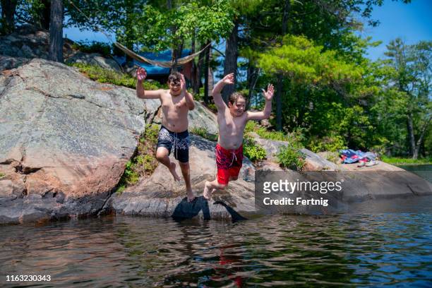 two brothers swimming in a beautiful northern lake on a summer day. - cottage family stock pictures, royalty-free photos & images