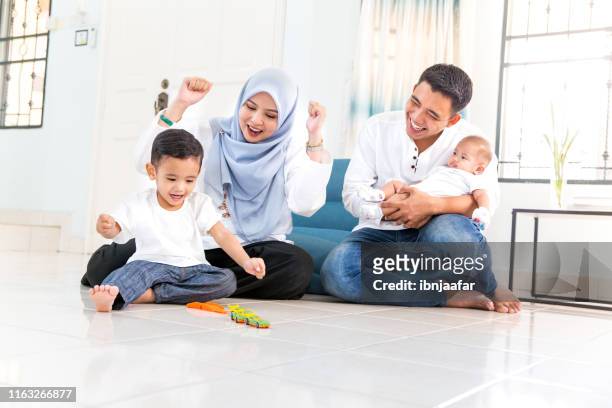 mooie jonge familie met tijd doorbrengen in huis - malaysia father and son stockfoto's en -beelden
