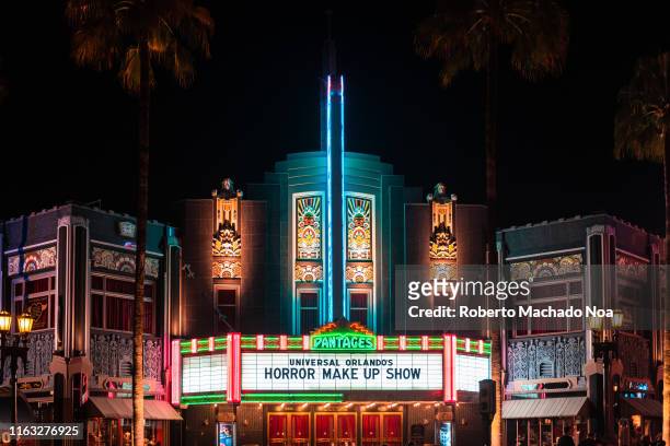An illuminated movie theater during the nighttime. The scene is taken in the Universal Studios Theme Park which is a major tourist attraction in the...