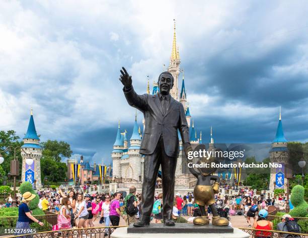 Walt Disney and Mickey Mouse statue inside of the Magic Kingdom theme park . The Cinderella castle can be seen in the background.