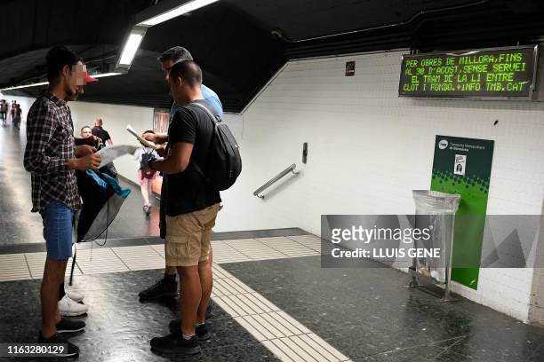 Two police officers in plainclothes check the identification documents of two presumed pickpockets at a metro station in Barcelona on August 14,...