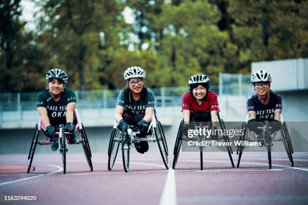 young female wheelchair racers prepare for competition at a track and field event - carrera de sillas de ruedas fotografías e imágenes de stock