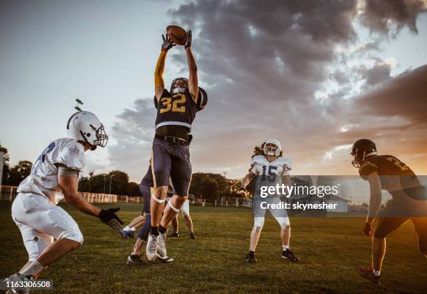 catching the ball on american football match! - american football player catch stock pictures, royalty-free photos & images