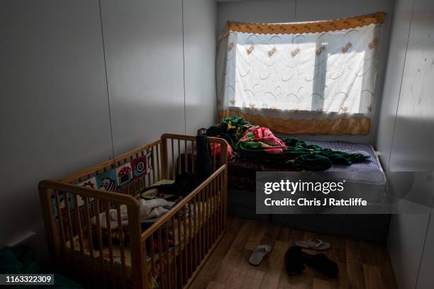 Abderrahim Yagoub sleeps after working a night shift as his wife Nasibah Yagoub prepares lunch for their 7 month old son Youssef at a development of...