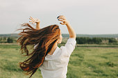 Close up portrait of beautiful carefree long hair girl in white clothes in field, view from back. Sensitivity to nature concept