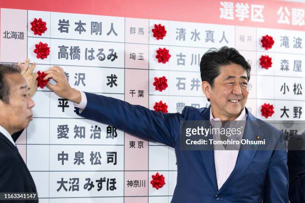 Japan's Prime Minister and ruling Liberal Democratic Party President Shinzo Abe and Secretary-General Toshihiro Nikai place a red paper rose on a LDP...