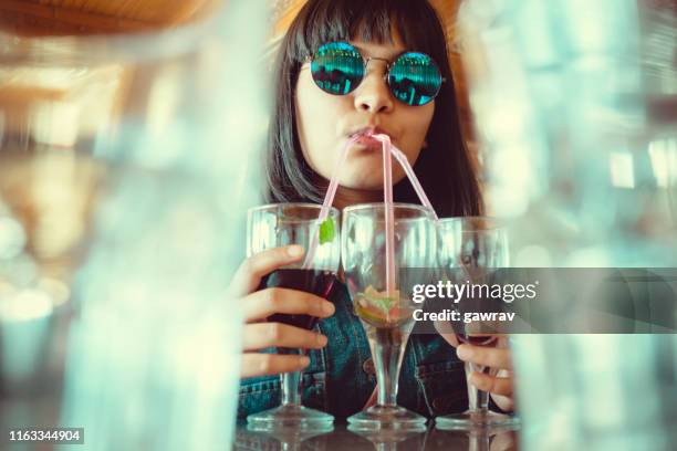 jonge vrouw drinkt drie glazen mock-tail tegelijk. - cocktail and mocktail stockfoto's en -beelden