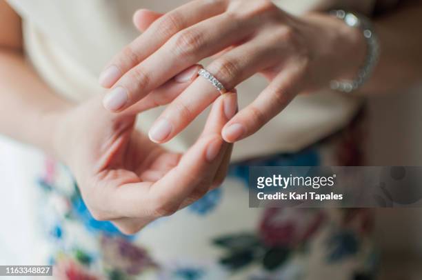 a young woman is wearing her wedding ring - taking off wedding ring stock pictures, royalty-free photos & images