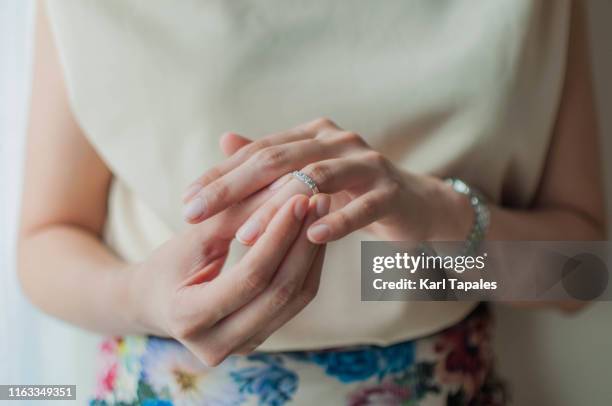 a young woman is wearing her wedding ring - リング ストックフォトと画像